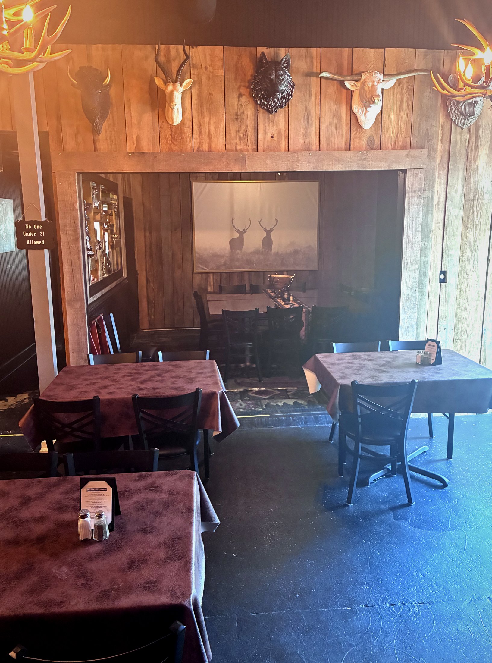 The dining room at 329 — rustic wood, mounts, set tables